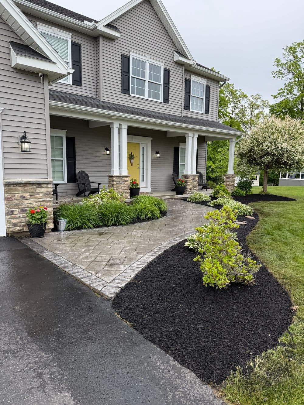 Modern home exterior with landscaping, charming porch, and pathway featuring stone pavers.